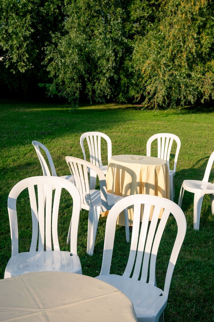 White plastic chairs and tables arranged outdoors in Pierrefonds, summertime ambiance.